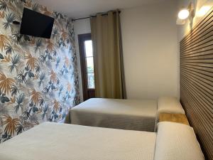 sypialnia z dwoma łóżkami i telewizorem na ścianie w obiekcie Hosteria Gelin de Gajano w mieście Gajano