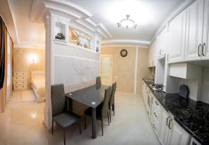 - une cuisine avec des placards blancs, une table et des chaises dans l'établissement Apartments U Ratushi, à Kamianets-Podilsky