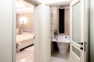 La salle de bains est pourvue d'une baignoire, d'un lavabo et d'un lit. dans l'établissement Apartments U Ratushi, à Kamianets-Podilsky