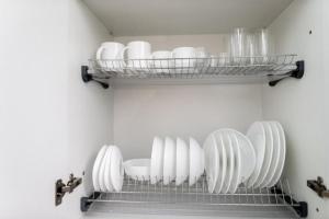 une cuisine avec des assiettes et des bols blancs sur une étagère dans l'établissement Apartments U Ratushi, à Kamianets-Podilsky
