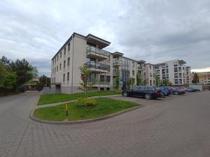 un estacionamiento con autos estacionados frente a un edificio en Apartament Łokietka, en Radomsko