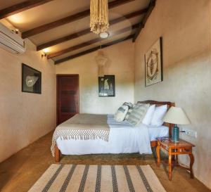 a bedroom with a bed and a table with a lamp at Vaayu Kula mandrem in Mandrem