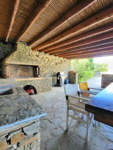 a patio with a stone fireplace and a stone table at Andros Eco Home in Gavrio