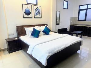 1 dormitorio con 1 cama blanca grande con almohadas azules en Backpacker's Nest en Amritsar