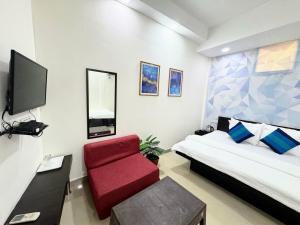 a bedroom with a red chair and a tv at Backpacker's Nest in Amritsar