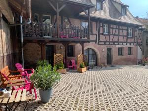 an outdoor patio with pink chairs and a building at Gite Terrasse Le Doux Refuge à Beblenheim Parking privé in Beblenheim