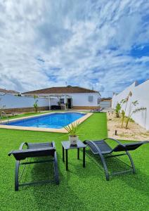 a yard with two chairs and a swimming pool at Villas Luins in Chiclana de la Frontera