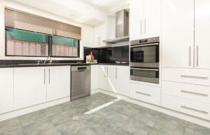 una cocina con armarios blancos y electrodomésticos de acero inoxidable en Varyam House, en Mildura