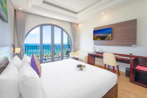 a hotel room with a bed and a desk and a window at Alani Hotel & Spa in Da Nang