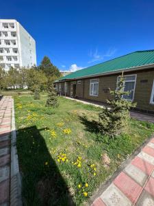 a yard with yellow flowers in front of a building at AiDaMaX #1 in Cholpon-Ata