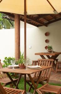einen Holztisch und Stühle unter einem Sonnenschirm in der Unterkunft Casa do Bougainvillea Mundaú-Trairi-Ce in Mundaú