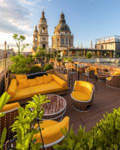 a rooftop patio with yellow furniture and a clock tower at Aria Hotel Budapest by Library Hotel Collection in Budapest