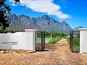 a gate to a vineyard with mountains in the background at Auberge La Dauphine Guest House in Franschhoek