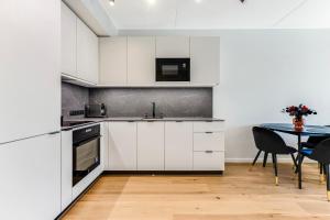 a kitchen with white cabinets and a table with chairs at 15 korruse premium katusekorter in Tallinn