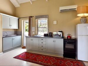 a kitchen with white cabinets and a black refrigerator at Auberge La Dauphine Guest House in Franschhoek