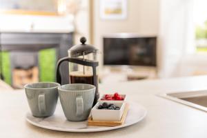 einen Teller mit zwei Tassen und eine Kaffeekanne auf der Theke in der Unterkunft Elizabeth House 1 - By Luxury Apartments in Cheltenham