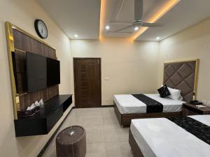 a hotel room with two beds and a tv at Gold Pine Hotel and Apartments in Lahore