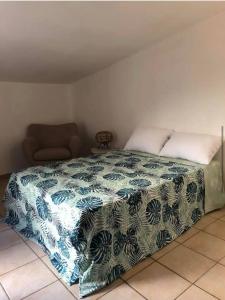 a bedroom with a bed with a blue and white blanket at La maison de vacances in Lauris