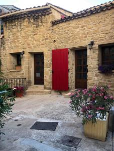 a stone building with a red door and some flowers at La maison de vacances in Lauris