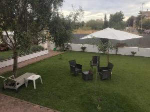 a patio with chairs and an umbrella on a lawn at Alloggio Turistico in Focene