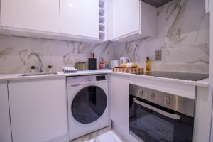 a white kitchen with a washing machine and a sink at Oxford Street Grandeur - Perfect for Large Groups in London