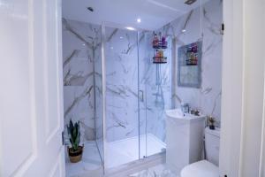 a white bathroom with a shower and a toilet at Oxford Street Grandeur - Perfect for Large Groups in London
