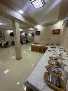 a large room with a table with plates on it at Sharq Plaza in Bukhara