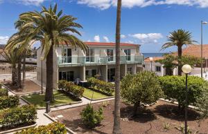 un edificio con palmeras y el océano en el fondo en Smartr Maspalomas Corinto en Playa del Inglés