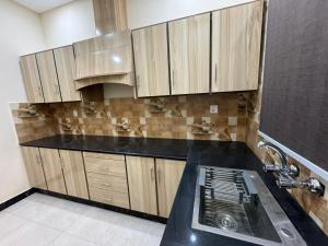 una cocina con armarios de madera y fregadero en Gold Pine Hotel and Apartments en Lahore