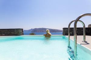 a woman sitting in a swimming pool at Charisma Suites in Oia
