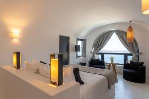 a bedroom with a large bed and a large window at Charisma Suites in Oia