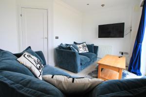 a living room with two blue couches and a table at Contemporary beachside apartment in St Merryn