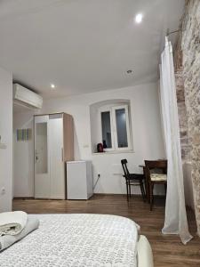 a bedroom with a bed and a table and a refrigerator at Sebenico Luxury Rooms 2 in Šibenik