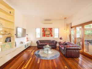 a living room with two leather couches and a table at 6KM to CBD Convenient 5BR Queenslander Coorparoo in Brisbane