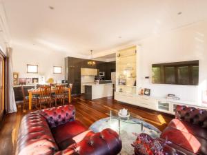 a living room with a leather couch and a kitchen at 6KM to CBD Convenient 5BR Queenslander Coorparoo in Brisbane