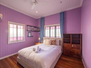 1 dormitorio con paredes moradas y 1 cama grande en 6KM to CBD Convenient 5BR Queenslander Coorparoo en Brisbane