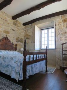 ein Schlafzimmer mit einem Bett in einer Steinmauer in der Unterkunft Casa Pita Caminha in Caminha