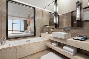 baño con bañera y lavamanos y cama en Crowne Plaza Beihai Silver Beach, an IHG Hotel, en Beihai
