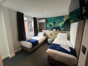 a hotel room with two beds and a window at Elberg Hotel & Apartments in Mouscron