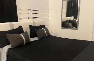 a white bed with black pillows and a mirror at Palese Profumo di Mare in Santo Spirito