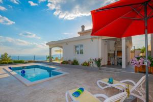 a house with a swimming pool and a red umbrella at Villa Mira Mel mit privaten Pool - Makarska Exklusiv in Makarska