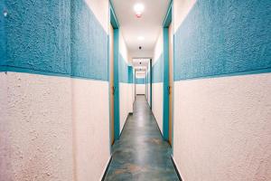 un corridoio con pareti bianche e blu e un corridoio lungo di FabHotel Royal King I a Surat