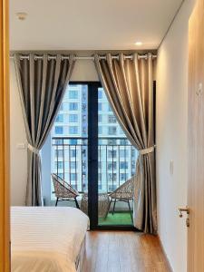 a bedroom with a bed and a large window at Mon Cherry Apartment -Greenbay Garden Ha Long in Ha Long