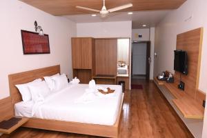 1 dormitorio con 1 cama blanca y TV en Varaha Residency Lodging and Banquet, en Hubli