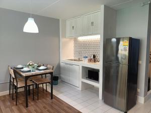 a kitchen with a table and a stainless steel refrigerator at DHIresidence at Impact,Muangthongthani in Pak Kret