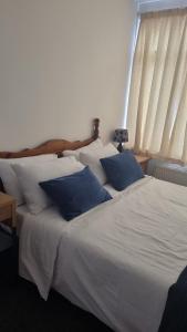Fair Oak Self-Catering Accomodation في سانداون: سرير أبيض مع وسائد زرقاء في غرفة النوم