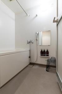 baño blanco con ducha y espejo en Plumeria en Naebochō