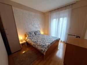 um pequeno quarto com uma cama e uma janela em SAN em Čačak