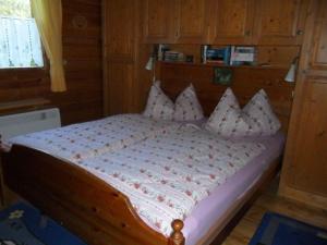 um quarto com uma cama de madeira e almofadas em Komfortables-Ferienblockhaus-Nr-27-56-qm-bis-4-Personen-Viechtach-Jaegerpark em Viechtach