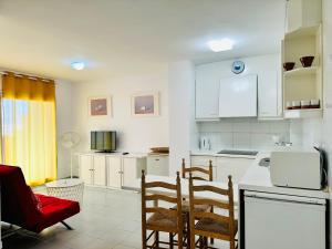 a kitchen with white cabinets and a red chair at Roc Mar 2 5C - Apartamento cerca del centro y de la playa - terraza con vistas al mar y al puerto in Roses